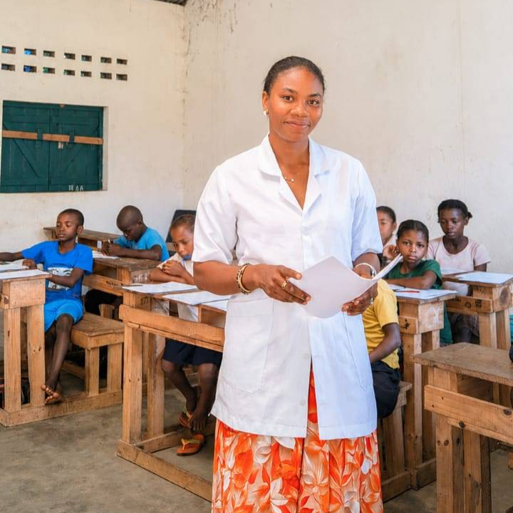 An image of Flavine standing in front of seated school children