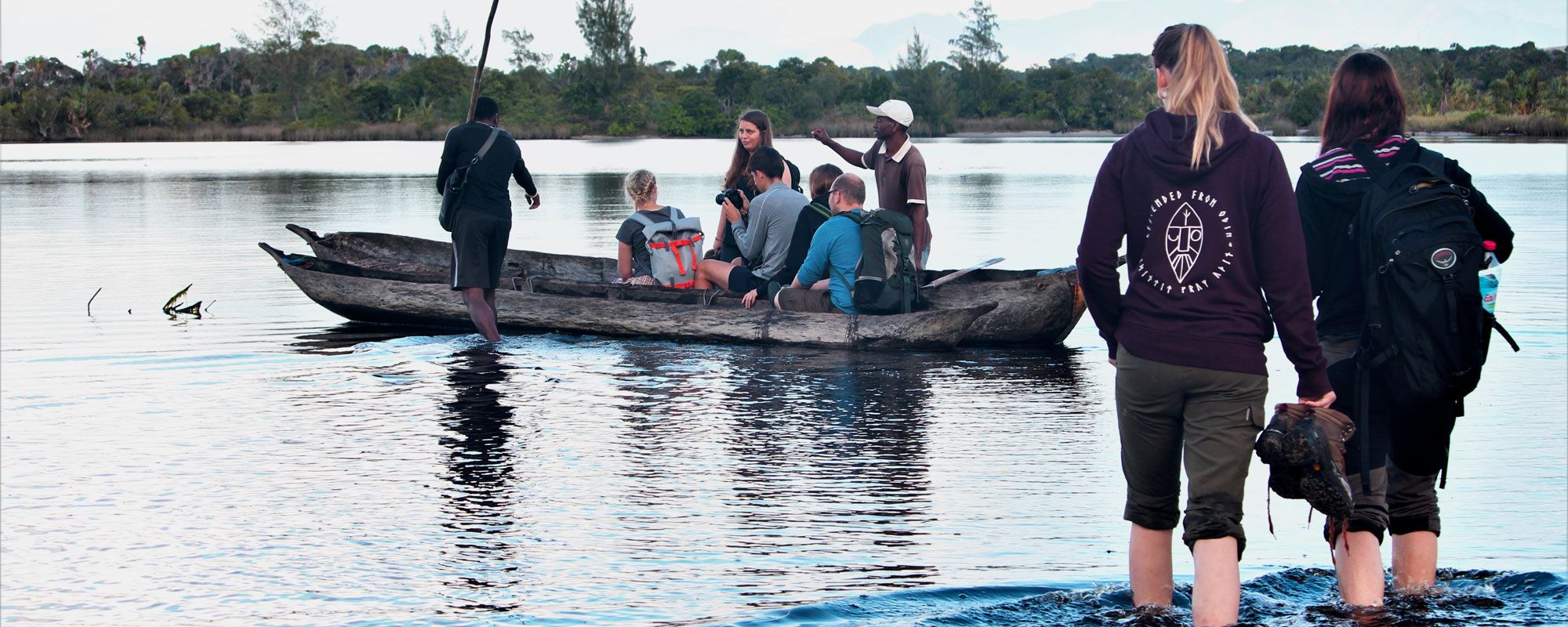 Volunteers climbing into a traditional wooden canoe in frontier Madagascar