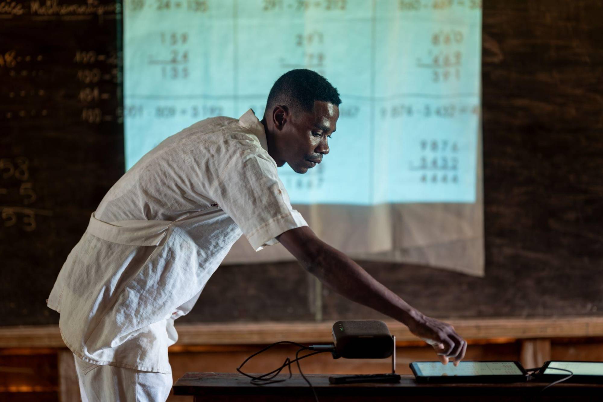 A teacher using a tablet and projector