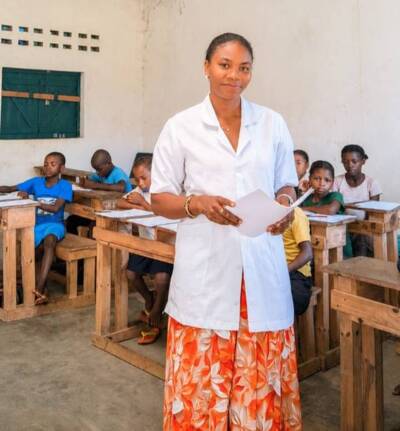 An image of Flavine standing in front of seated school children