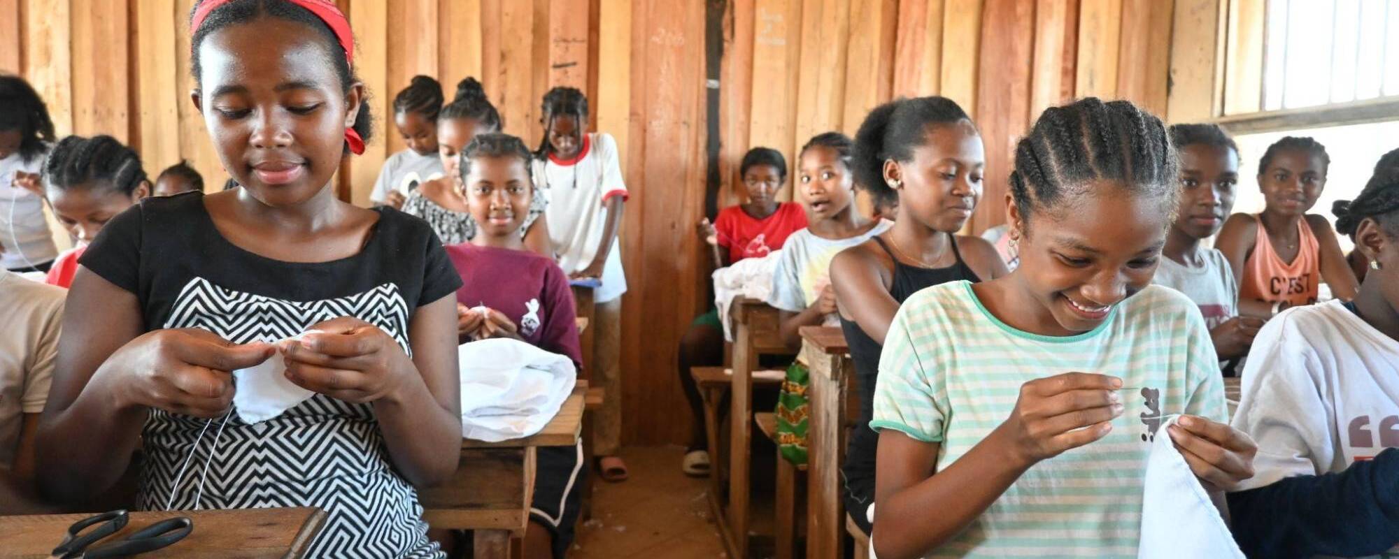 Women sitting at desks constructing menstrual pads